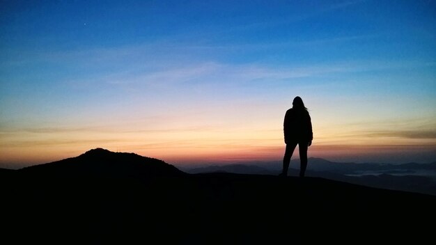 Silhouette man standing on mountain against sky during sunset