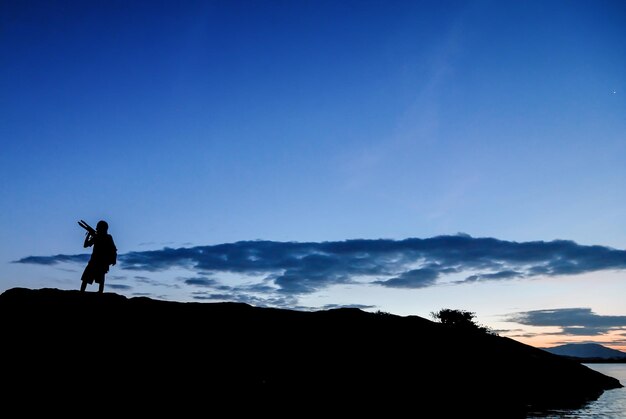 Photo silhouette man standing on mountain against sky during sunset