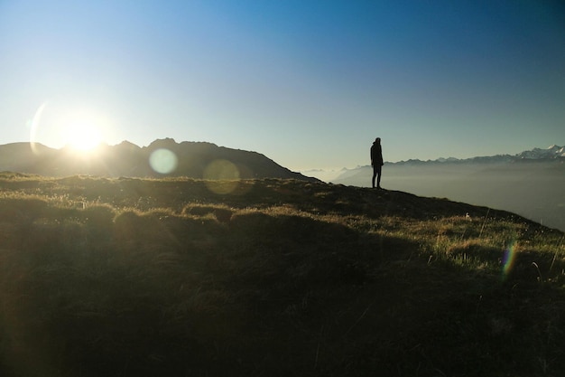 Silhouette man standing on mountain during sunny day