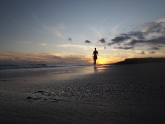 写真 夕暮れの空に向かってビーチに立っているシルエットの男