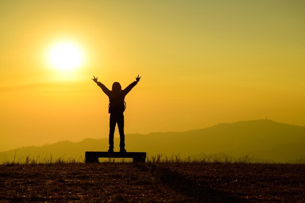 写真 夕暮れの空に向かってフィールドに立っているシルエットの男