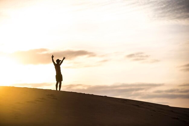 写真 夕暮れの空に照らして地面に立っているシルエットの男