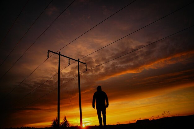 写真 夕暮れの空に向かって通りで立っているシルエットの男