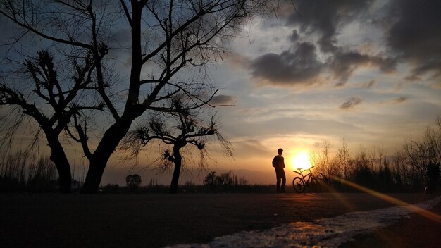 Silhouette man standing on road against sky during sunset