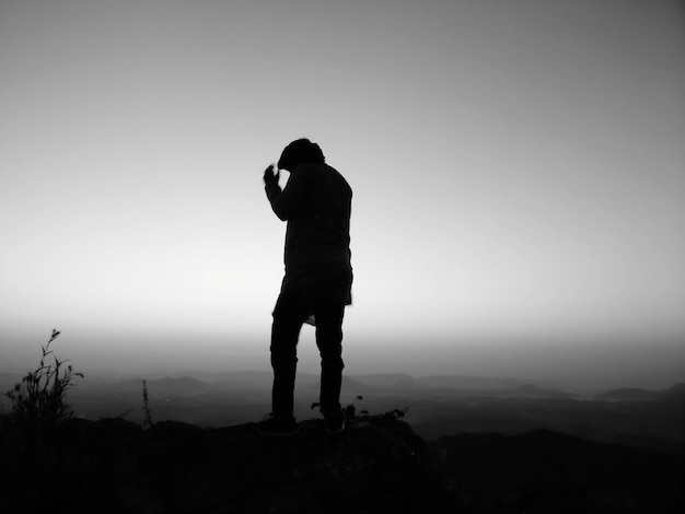 Foto silhouette di un uomo in piedi su una roccia contro un cielo limpido