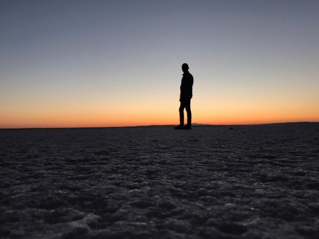 Foto uomo a silhouette in piedi sul mare contro il cielo durante il tramonto