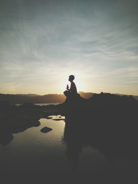 Foto silhouette uomo in piedi sulla riva contro il cielo durante il tramonto