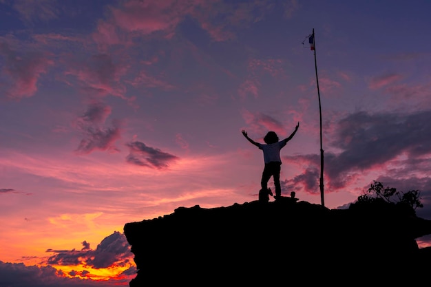 silhouette of man standing on top of mountain with happy expression