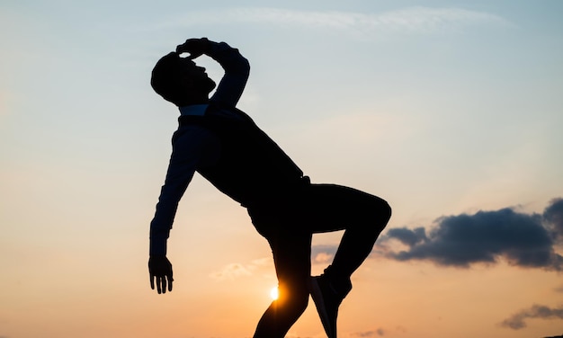 Silhouette of man stepping in sense of freedom on sunrise sky success