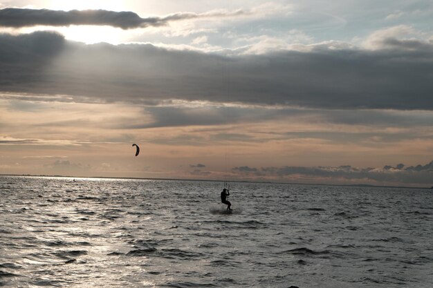 Silhouette man surfing in sea against sky during sunset