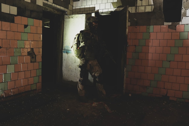 Silhouette of a man in uniform with a weapon in an old corridor\
in red smoke