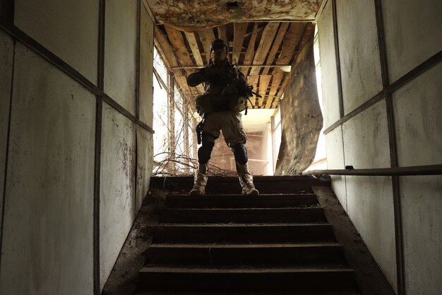 Sagoma di un uomo in uniforme con un'arma in una vecchia scala in un corridoio di vetro in fumo rosso