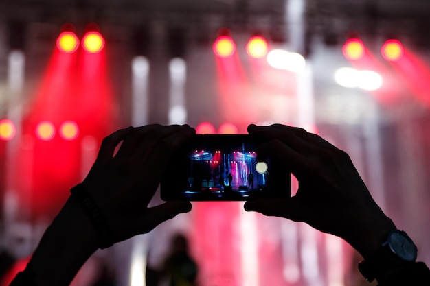 스마트폰을 사용하여 콘서트에서 비디오를 찍는 남자의 실루엣