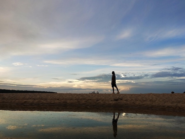 Silhouette of a man walking along the coast