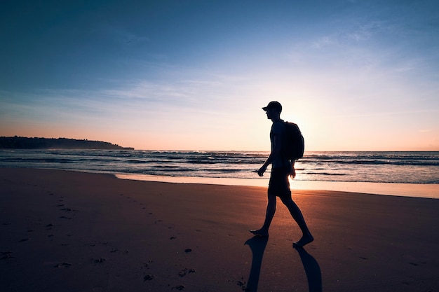 Silhouette man walking on beach against sky during sunset