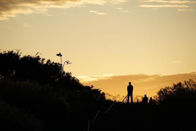 silhouette man walking on field against sky during sunset