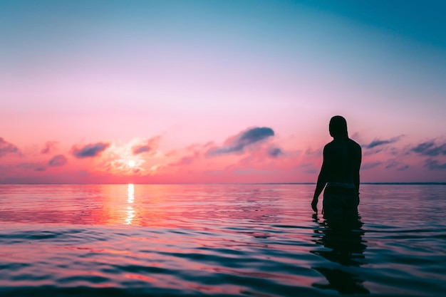 Siluetta di un uomo nell'acqua al tramonto