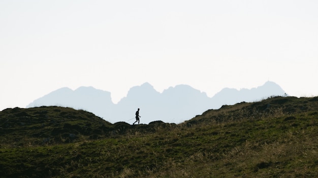 Photo silhouette of a man who practices nordic walking in the mountains