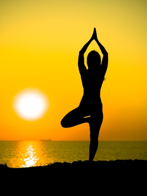 Photo silhouette man with arms outstretched against sky during sunset