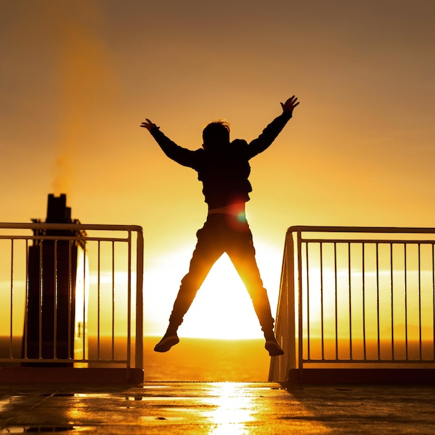 silhouette man with arms outstretched against sky during sunset