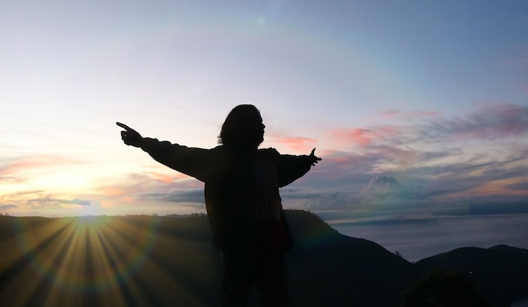 Photo 夕暮れの空に向かって腕を伸ばした男のシルエット