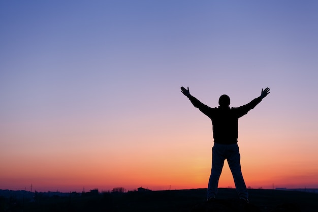 Silhouette of man with arms raised up and beautiful sky. Element of design. Summer sunset. Background