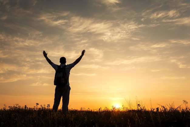 Silhouette of man with arms raised up and beautiful sky