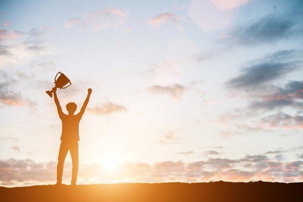 Silhouette man with arms raised while standing against sky during sunset