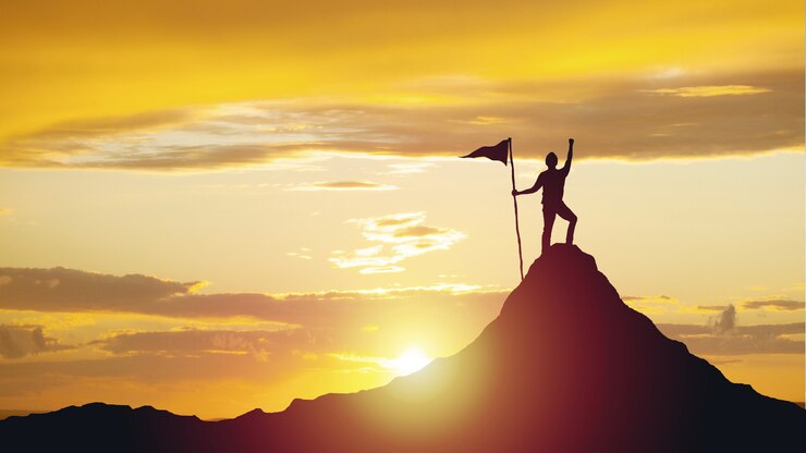 Photo silhouette of man with flag on mountain top over sky and sun light surface