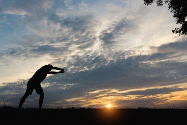 夕日の中で運動している男性と男のシルエット。