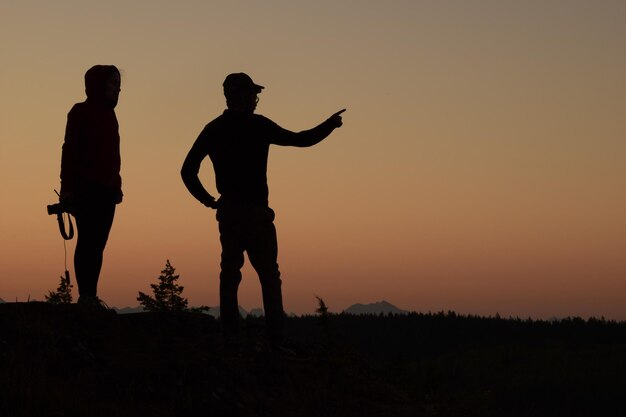 Photo silhouette men standing against sky during sunset