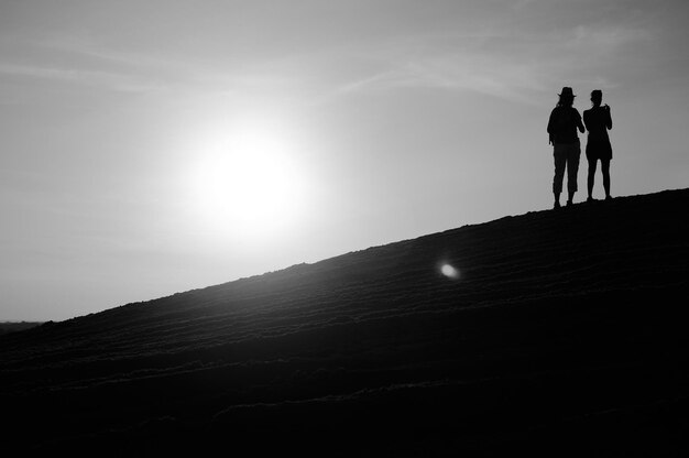 Silhouette men standing on mountain against sky during sunset