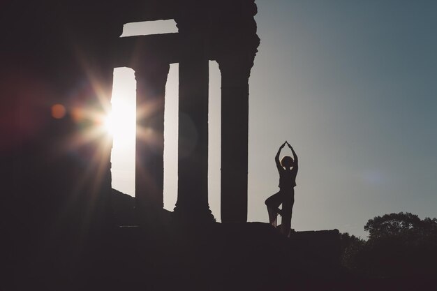 Photo silhouette mid adult woman exercising at old ruin against sky during sunset