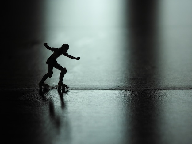 Silhouette miniature woman skating on the floor.