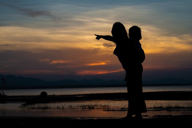 Silhouette of mom and daughter at seaside on sunset