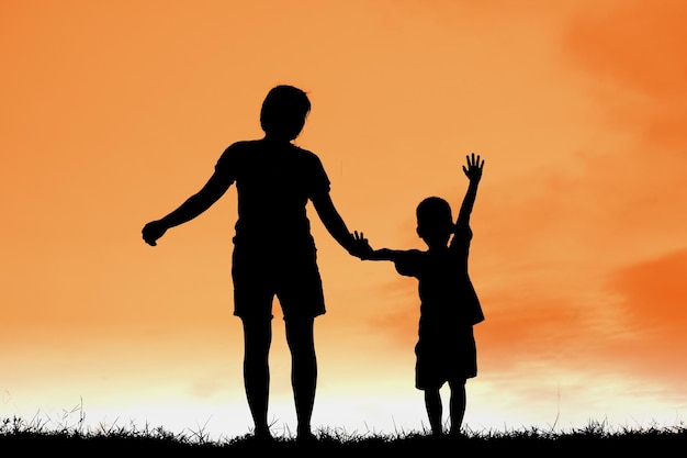 Silhouette of mother and child against orange sky during sunset