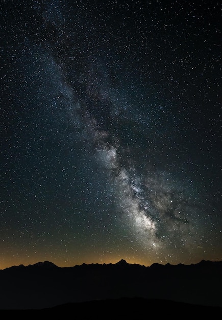 夜の星のフィールドに比べて山のシルエット