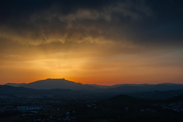 A silhouette of a mountain against a sunset sky.