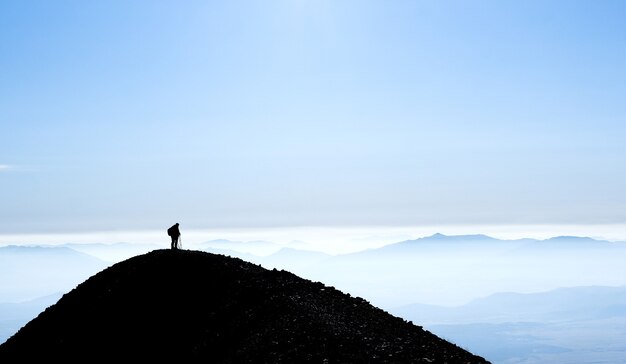 Silhouette di montagna con un escursionista in piedi sulla cima