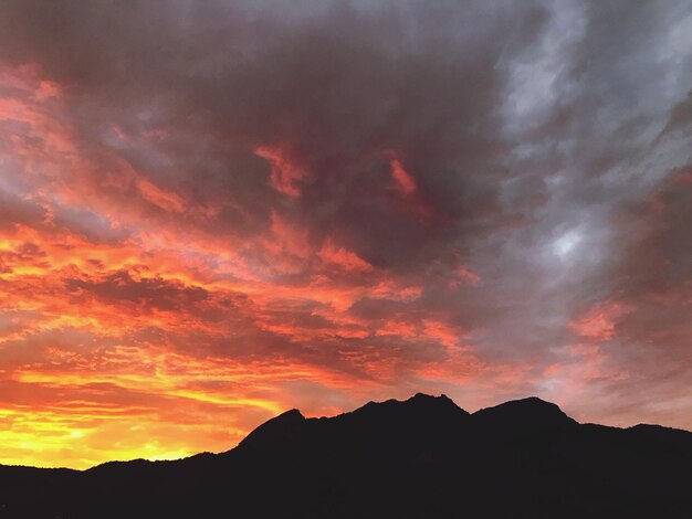 Silhouette mountains against dramatic sky during sunset