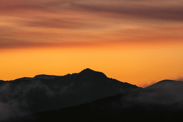 Силуэт гор и оранжевого неба во время красивого заката