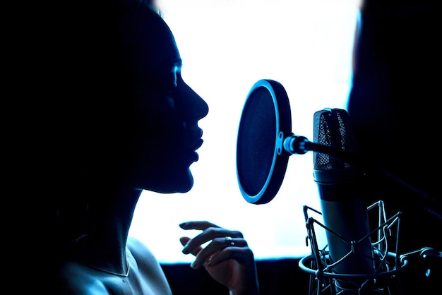 Silhouette di donna appassionata di musica e microfono in studio professionale cantante davanti a un microfono primo piano