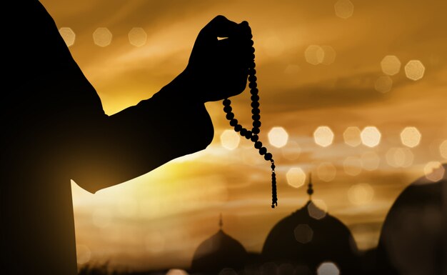 祈りビーズで祈るイスラム教徒の男性のシルエット