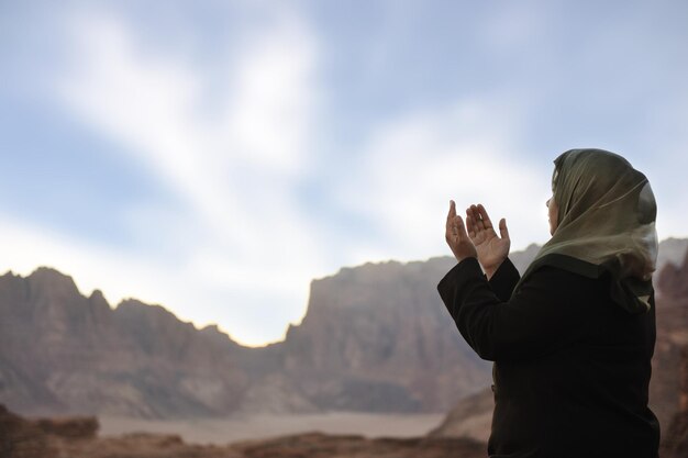 Silhouette di una donna musulmana che prega nel deserto