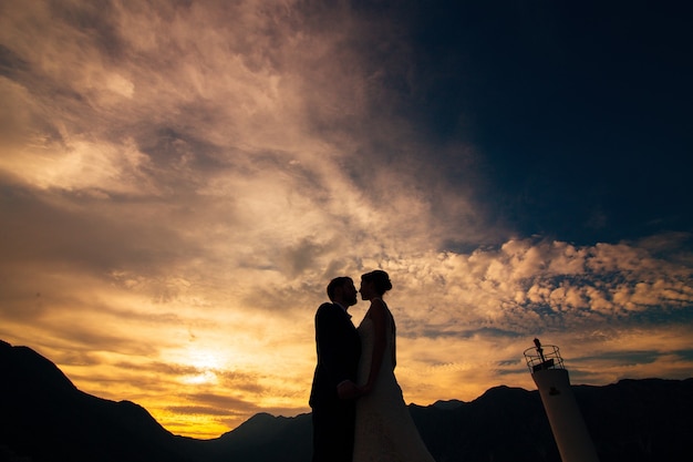 Silhouette of a newlywed couple on the background of the setting sun