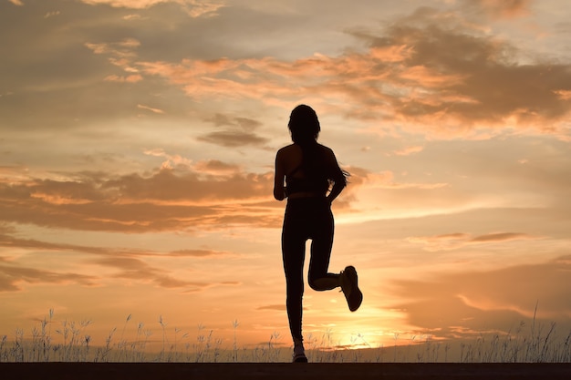 Silhouette od young woman running.sporty young woman running on\
road in beautiful nature.