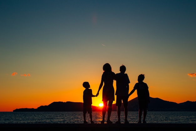 写真 夕日と海を背景に子供連れの家族のシルエット