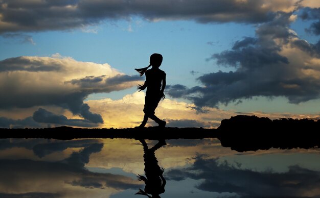 写真 海の背景で踊っている小さな女の子のシルエット