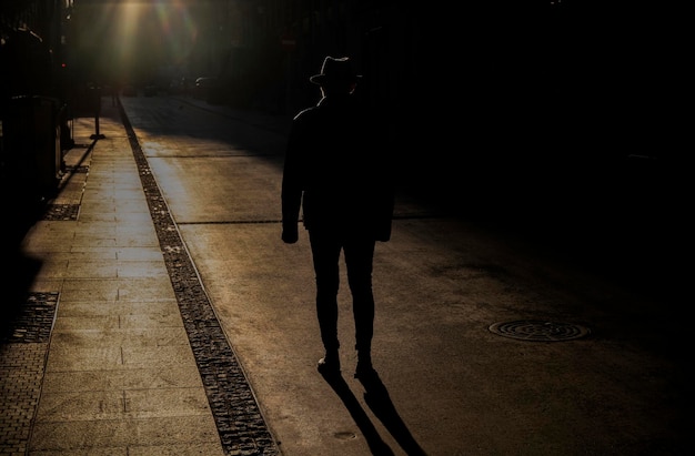 Фото Силуэт взрослого мужчины в шляпе на улице во время захода солнца в мадриде, испания