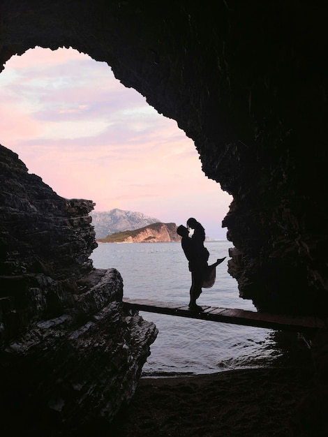 Фото Силуэт пары в пещере перед красивым морским пейзажем на пляже могрен